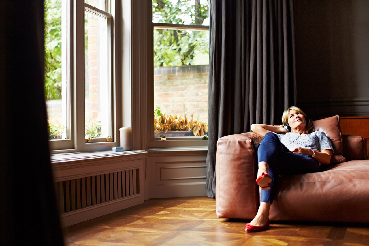 510073322 Shot of a mature woman lying back on her sofa listening to music on headphones